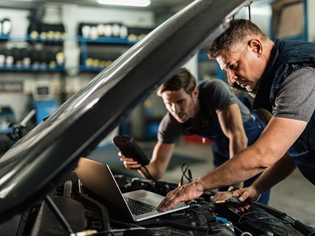 Two car mechanics running a diagnostic check on an engine.