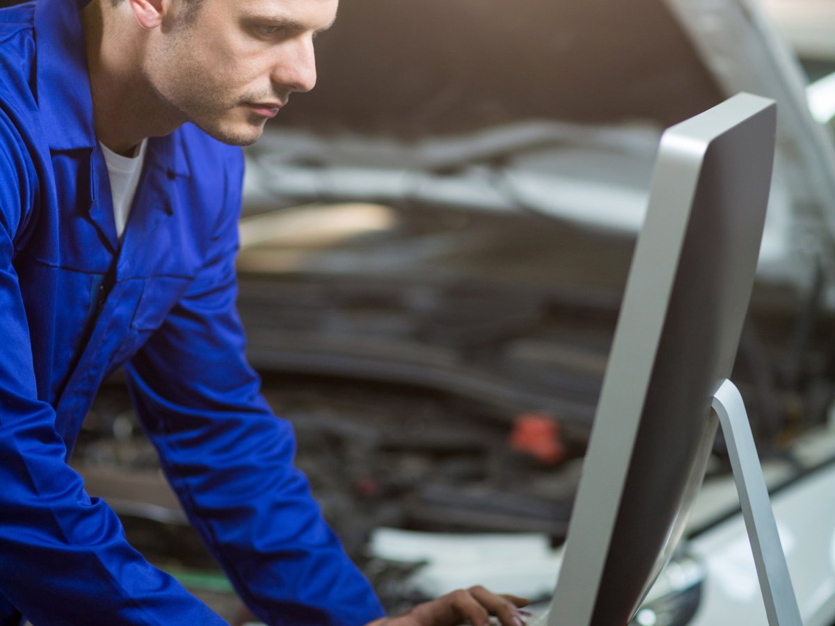 Car mechanic working at a computer in the workshop.